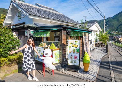 YUFUIN,OITA,JAPAN-SEPTEMBER 19,2019:  Girl With A Snoopy Doll In Front Of The Soft Serve Shop At Yufuin Walking Street