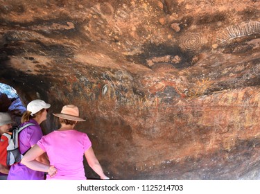 Yulara, Australia - Jun 10, 2018. Tourist Watching Aboriginal Rock Drawings At Uluru. Australian Indigenous Art Is The Oldest Unbroken Tradition Of Art In The World.