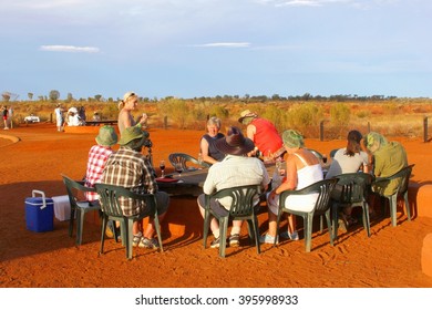 YULARA, AUSTRALIA - March 25, 2016. Tourist Group Enjoys A Picnic And Wine In The Desert At Sunset In Uluru Kata Tjuta National Park. Uluru Is A Popular Tourist Destination For Holiday Vacation.