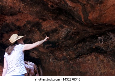 YULARA, NT - MAY 23 2019:Australian Woman Looking At Cave Painting In Uluru (Ayers Rock). Uluru Is Australia's Most Natural Icon And The Focal Point For Australia Of Australian Indigenous People. 