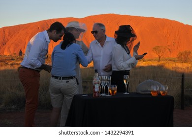 YULARA, NT - MAY 23 2019:Group Of Australian People Celebrating During Uluru Ayers Rock Sunset Tour, Australia's Most Natural Icon And The Focal Point For Australia Of Australian Indigenous People