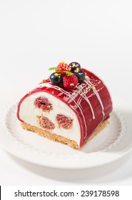Yule log of white chocolate mousse, stuffed with raspberry puree sponge rolls, glazed with raspberry jelly, garnished with white chocolate, fresh berries, and gold leaf (also know as Buche de Noel)