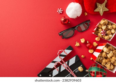 Yuletide Movie Magic: Top-view photo showcasing a movie clapper, 3D glasses, delectable popcorn, Santa's hat, baubles, star decor, candy canes on a red background with text or ad space - Powered by Shutterstock