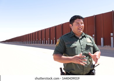 Yuma Sector, Ariz. / US - April 11, 2013: A Customs And Border Protection Agent Standing By A Section Of Landing-mat Fencing In The US-Mexico Border Wall. 1605