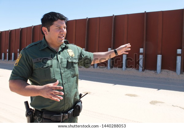 Yuma Sector, Ariz. / US -\
April 11, 2013: A Customs and Border Protection agent standing by a\
section of landing-mat fencing in the US-Mexico border wall.\
1607