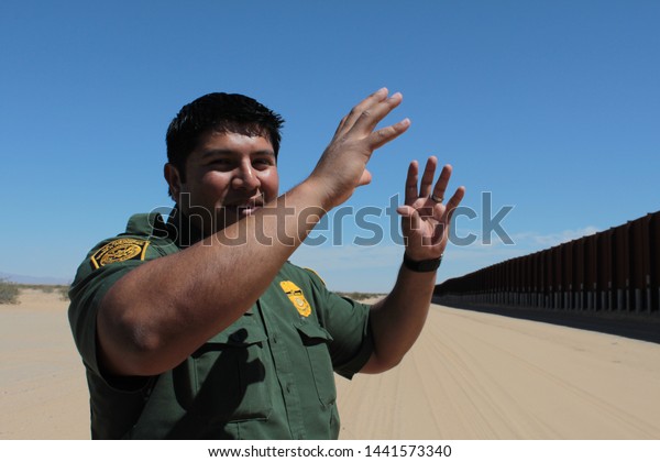 Yuma Sector, Ariz. / US -\
April 11, 2013: A Customs and Border Protection agent standing by a\
section of landing-mat fencing in the US-Mexico border wall.\
1619