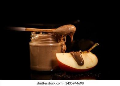 Yummy Chocolate Peanut Butter In Small Glass Jar With Wooden Spoon On Top Served With Slice Of Apple