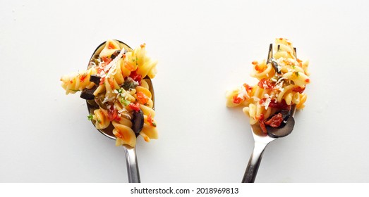 Yummy fusilli pasta bolognese on a spoon and fork in the white background - Shutterstock ID 2018969813