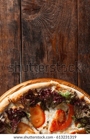 Yummy italian pizza served on wooden background at the bottom with free space for text. Fast food restaurant photo.