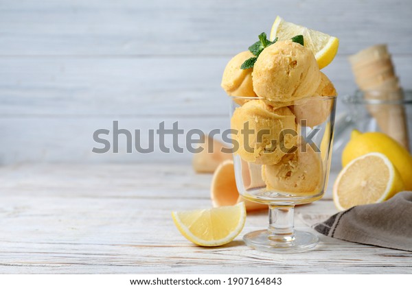Yummy lemon ice cream served on white wooden table,\
space for text