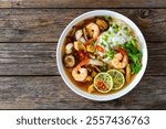 Yunnan hot pot - Chinese soup with chicken breast and shrimps on wooden table