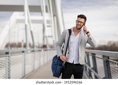 Yuppie outdoors talking on smartphone and smiling. Happy young businessperson on the bridge holding bag