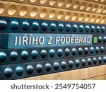 Jiřího z Poděbrad metro station in Prague, Czechia. Sign of the location name in the subway tunnel. Yellow and blue aluminum shapes are mounted to the wall. Public transportation in the big city.