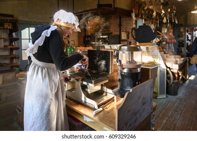 ZAANSE SCHANS, NETHERLANDS - JANUARY 22,2017: Beautiful girl in traditional dresses cook waffles in a pastry shop in Zaanse Schans. The location is famous for the historical windmills
