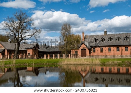 Zagare manor stud farm complex by the pond with reflection on a sunny spring day, Lithuania