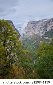 Zagori gorge with clouds, trees, blue sky and mountians.