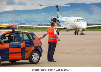 ZAGREB, CROATIA - APRIL 28, 2013: Aircraft marshaller standing by the Follow Me car at Pleso Airport. 
