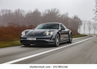 Zagreb, Croatia - December 8, 2020: Man is driving Porsche Taycan fast on the road. Taycan is all electric four door sports coupe made by famous German sports car manufacturer Porsche.