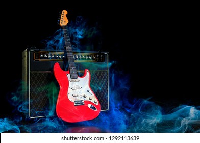 ZAGREB, CROATIA - JANUARY 10, 2012: Red electric guitar and amplifier surrounded by blue smoke on dark empty stage.