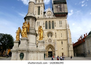 Zagreb, Croatia - June 15, 2019: Cathedral of the Assumption of the Blessed Virgin Mary and Mary column, landmarks in Zagreb, Croatia. Tourists sightseeing in front of the cathedral.