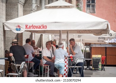 ZAGREB, CROATIA - JUNE 20, 2021: Old senior men, friends, croats, discussing in a crowd at the terrace of a bar restaurant in summer in the Croatian capital city, Zagreb.