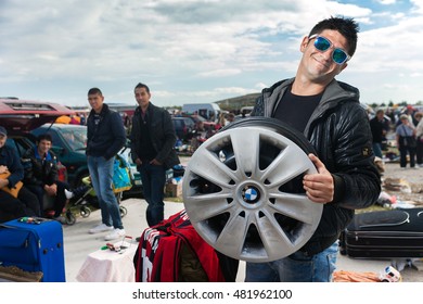 ZAGREB, CROATIA - OCTOBER 20, 2013: Roma Salesman Holding Used Car Rim At Zagreb's Flea Market Hrelic.