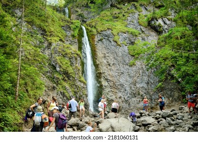 ZAKOPANE, POLAND - AUGUST 2021: Group of tourists admiring Siklawica Waterfall in Strazyska Valley in Tatra Mountain range, Poland.