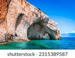 Zakynthos, Greece. Rock arches of Blue Caves from sightseeing boat with tourists in blue water of Ionian Sea. Greece holidays vacation tour with trip from Agios Nikolaos port.