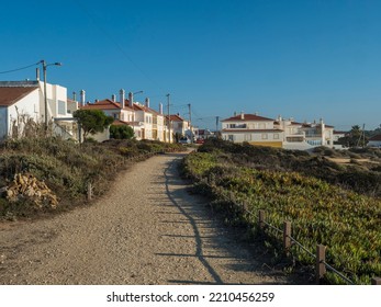 Zambujeira Do Mar, Odemira, Portugal, October 27, 2021: Gravel Footpath Road Leading From Beach To Small Resort Town With White And Yellow Houses. Clear Blue Sky. Rota Vicentina Coast