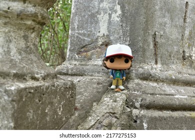 Zaporizhzhia, Ukraine - July 11, 2022: Illustrative Editorial Of Funko Pop Action Figure Of Dustin Henderson From Popular TV Series Stranger Things. Boy Standing On Fragment Of Large Old Stone Stairs.