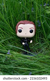 Zaporizhzhia, Ukraine - May 8, 2022: Funko Pop Vinyl Action Figure Of Marvel Avengers Superhero Black Widow Natasha Romanoff Standing On Meadow Among High Green Grass And Purple Wildflowers.