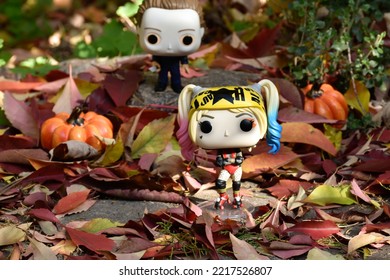 Zaporizhzhia, Ukraine - October 19, 2022: Funko Pop Action Figures. Serial Killer Michael Myers From Horror Movie Halloween Attacking With Knife Harley Quinn Walking In Fall Garden. Spooky Season. 