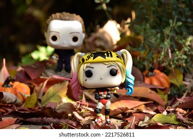 Zaporizhzhia, Ukraine - October 19, 2022: Funko Pop Action Figures. Serial Killer Michael Myers From Horror Movie Halloween Attacking With Knife Harley Quinn Walking In Fall Garden. Spooky Season. 