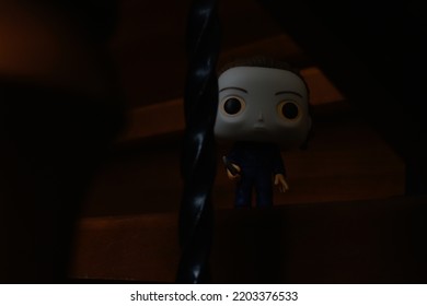 Zaporizhzhia, Ukraine - September 16, 2022: Funko Pop Vinyl Action Figure Of Serial Killer Michael Myers From Popular Horror Movie Halloween. Spooky Toy Looking Over Wooden Stairs In Dark House. 