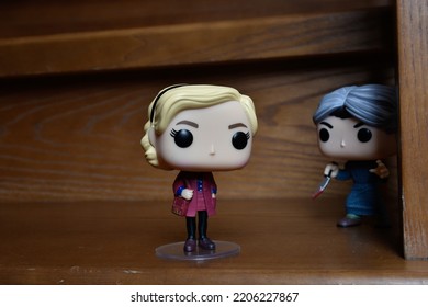 Zaporizhzhia, Ukraine - September 22, 2022: Funko Pop Action Figures Of Sabrina Spellman And Norman Bates From Movie Psycho. Killer Attacking Teenage Witch With Knife On Dark Wooden Stairs. 