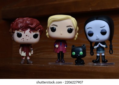 Zaporizhzhia, Ukraine - September 22, 2022: Funko Pop Vinyl Action Figures Of Beverly Marsh From Horror Movie It, Sabrina Spellman Witch With Cat Salem And Wednesday Addams Standing On Wooden Stairs.