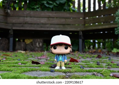 Zaporizhzhia, Ukraine - September 26, 2022: Funko Pop Vinyl Action Figure Of Teenage Boy Dustin Henderson From Popular TV Series Stranger Things. Toy In Autumn Garden, Paving Slabs With Green Moss.