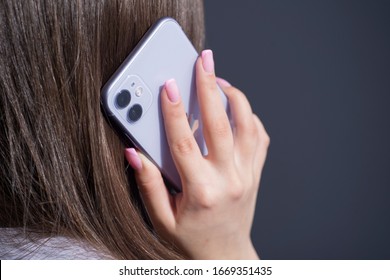 Zaporozhye. Ukraine. February 2020. Studio Portrait Of A Girl In A White Coat. The Doctor Holds In His Hand An IPhone 11 From Epl. On A Gray Background.