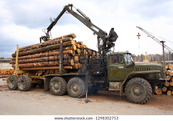 Zavodoukovsk city,\
Tyumen region, Russia, April 29, 2010: operator unloads manipulator\
timber trailer. Pine\
logs.