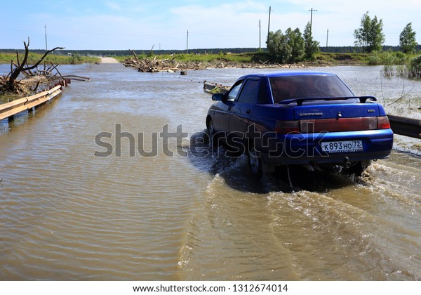 Zavodoukovsk\
city, Tyumen region, Russia, June 14, 2014: Tobol river Crossing\
over the flooded bridge. Floating\
cars.