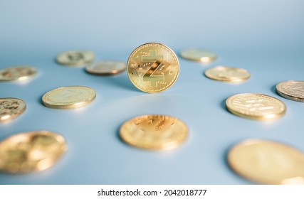 Zcash coin standing centrally placed among bunch of crypto coins on blue background. Close-up, soft focus. Banner with golden Zec token.