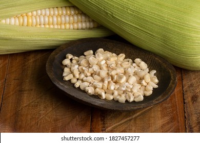 Zea mays - Wooden bowl with raw corn kernels, on wooden background.