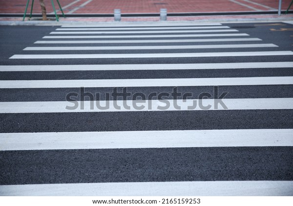 Zebra pedestrian crossing on the asphalt.\
The perspective receding into the\
distance.
