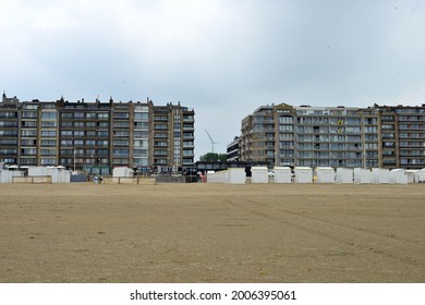 Zeebrugge, Belgium- July 11, 2021: Zeebrugge windturbine wings, terraced apartment facades in front of the beach. National holiday golden spurs, Flemish institution flags are hanging out the windows. 