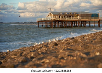 Zeeland, Holland - September 27, 2021: Beach Restaurant Zee In The Evening On The North Sea. Building Above The Water On The Stony Dam. Water Sportsmen Do Kiteboarding. Netherlands, Brouwersdam.