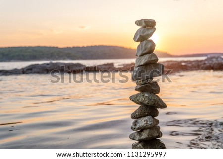 Zen balanced stones stacked on sea coast at sunset. Balance and equilibrium concept.