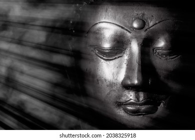 Zen buddhism and spiritual enlightenment. Mindful monochrome buddha face illuminated by mystical heavenly light. Peaceful esoteric expression of contemplation relating to meditation and the Universe