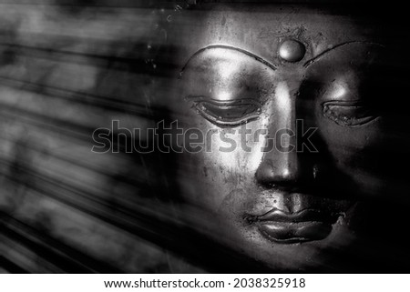 Zen buddhism and spiritual enlightenment. Mindful monochrome buddha face illuminated by mystical heavenly light. Peaceful esoteric expression of contemplation relating to meditation and the Universe