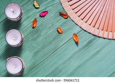 Zen Candle And Fan With Hieroglyphs On A Green Wooden Background, Close Up. Spa Concept Flat Lay.