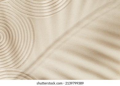Zen garden meditation sandy background for relaxation. Lines drawing in sand and shadows of palm leaves. Concept of harmony, balance and meditation, spa, massage, relax. Top view and copy space. - Shutterstock ID 2139799389